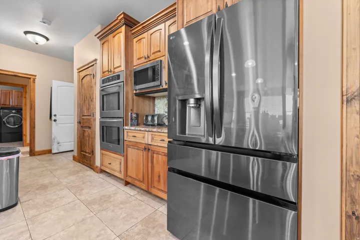 Built-in double ovens, stainless steel appliances, wood cabinetry, tile flooring, and a built-in microwave