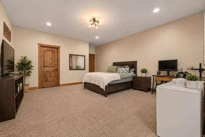 Spacious room with plush carpet flooring, recessed lighting, and a modern Sputnik-style ceiling fixture