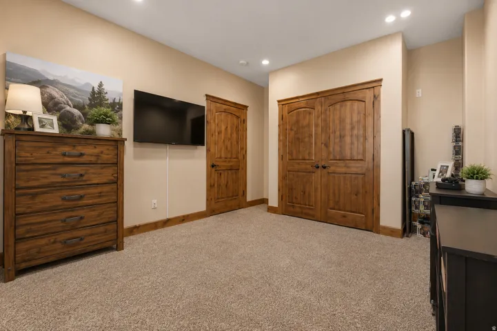 Neutral tone painted walls, recessed ceiling lighting, light-colored carpet flooring, and wood-finish doors