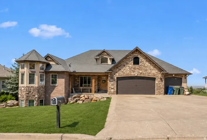 Front of home, with stone and brick exterior with a turret feature