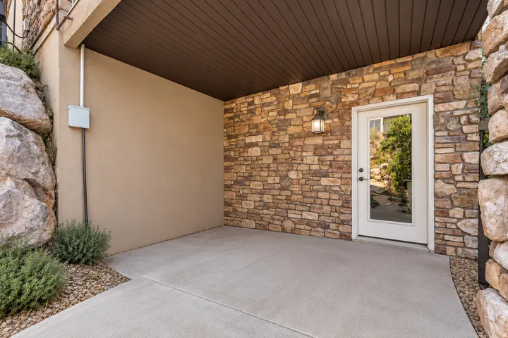 Expansive patio with stone veneer wall, stucco siding, and concrete flooring - (AI removed hot tub)