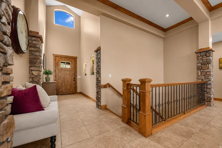 Two-story entryway with arched transom window, wood-finish front door with glass panes, natural stone veneer accents, and tile flooring