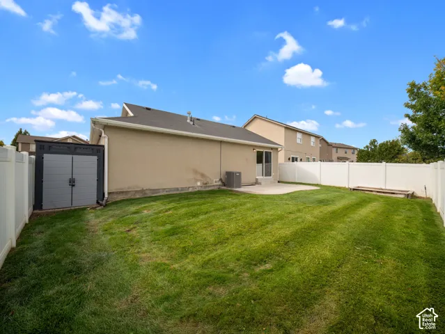 Expansive backyard featuring a manicured lawn, concrete patio, and privacy fencing