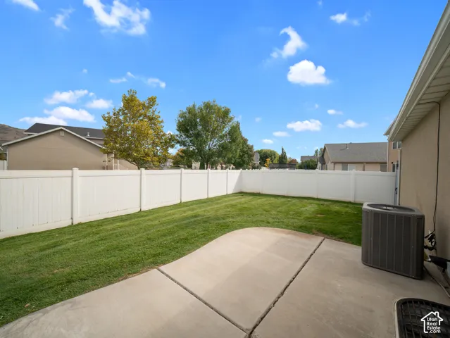 Manicured lawn, full privacy fencing, and concrete patio