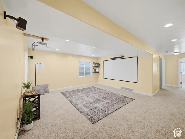 Spacious room featuring neutral carpeting, recessed ceiling lighting, and a mounted projection screen
