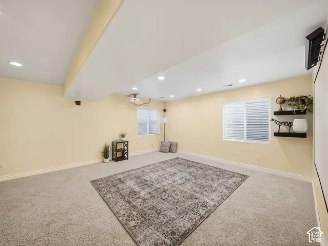 Carpeted room featuring recessed lighting, two windows with blinds, and built-in wall speakers