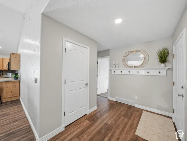 Wood-finish flooring, white trim, recessed ceiling lighting, and a white coat rack with shelf