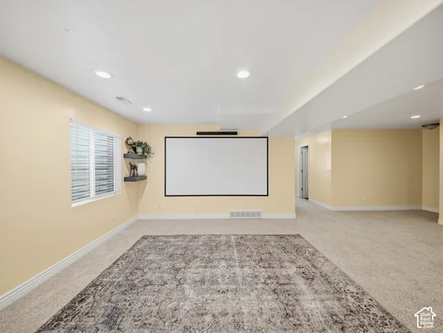 Recessed lighting, light-toned carpeting, window with horizontal blinds, built-in projection screen, and wall-mounted shelving