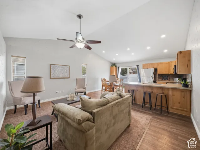 Vaulted ceilings with a ceiling fan, recessed lighting, wood-finish flooring, and light wood cabinetry with stainless steel appliances