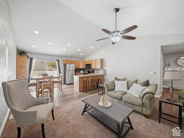 Vaulted ceilings with recessed lighting and a ceiling fan, wood-finish flooring, and light wood cabinetry with stainless steel appliances
