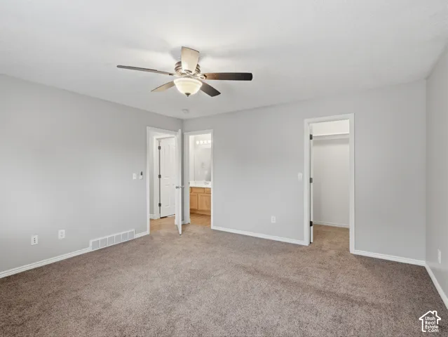 Plush carpet flooring, neutral wall tones, and a ceiling fan with integrated lighting