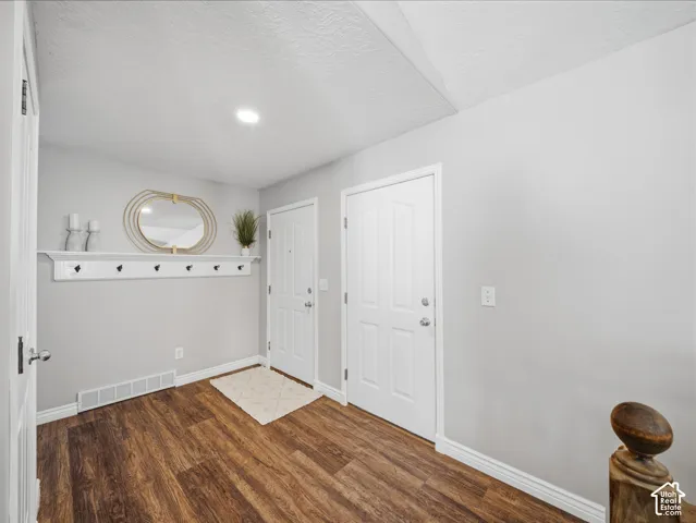 Wood-finish flooring, two paneled doors, and a built-in shelf with coat hooks
