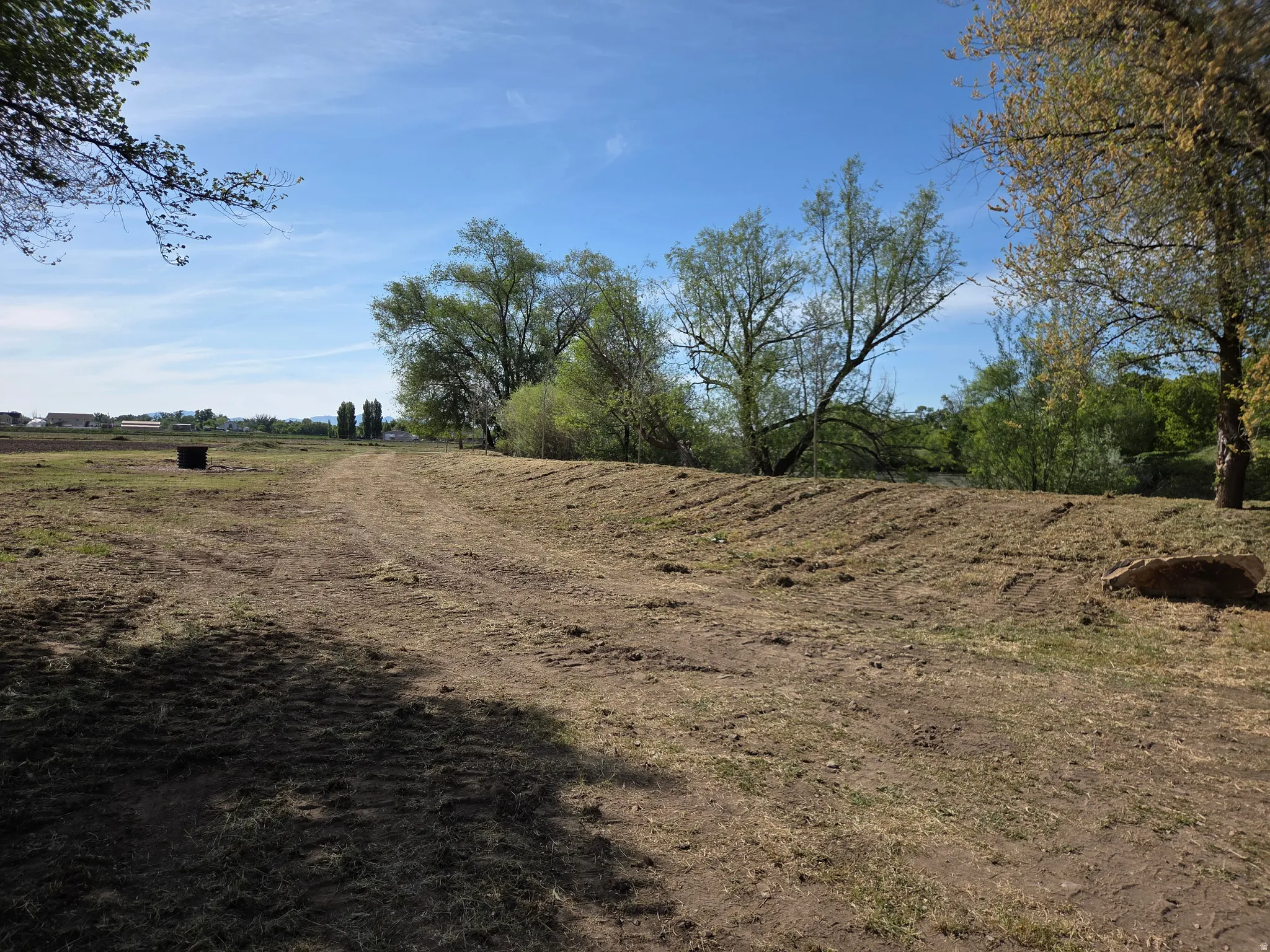 Expansive land with visible earthworks, mature trees, and natural vegetation
