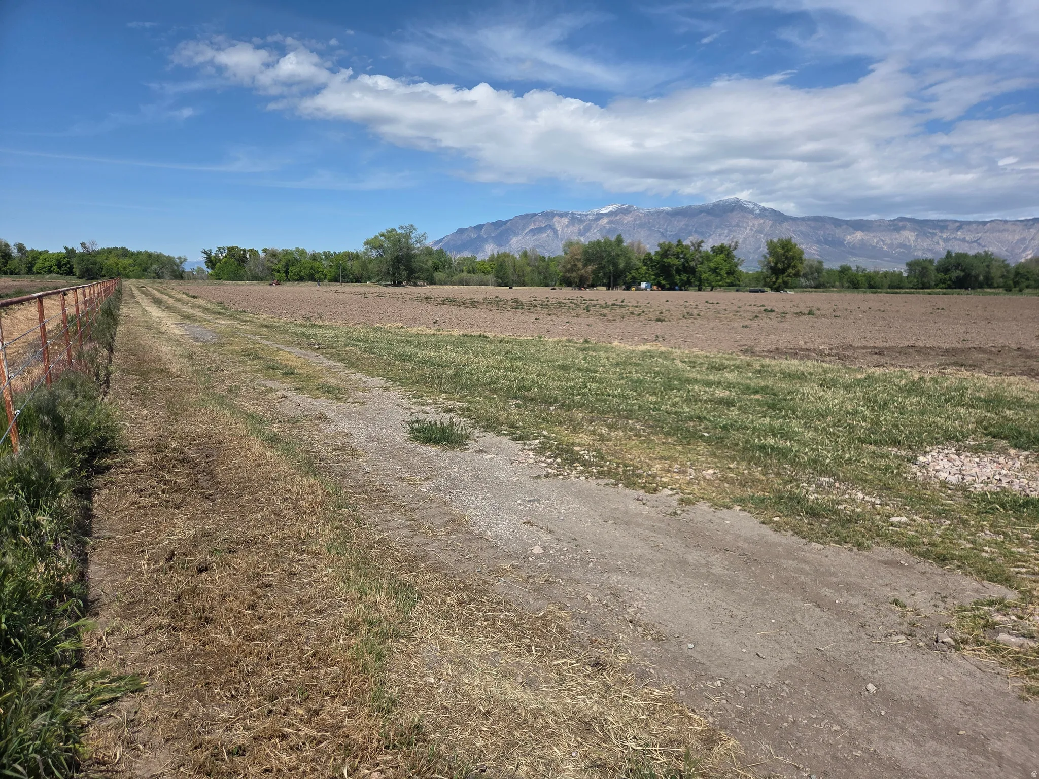 Expansive agricultural land featuring a wire fence and distant mountain range