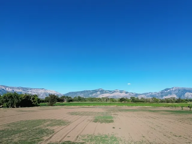 Expansive open terrain with visible cultivation patterns, framed by distant mountains and a clear sky