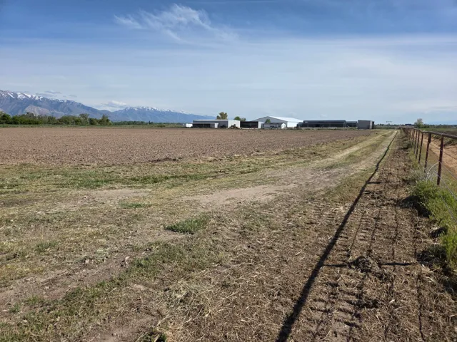 Expansive tilled field with distant mountains and a perimeter fence