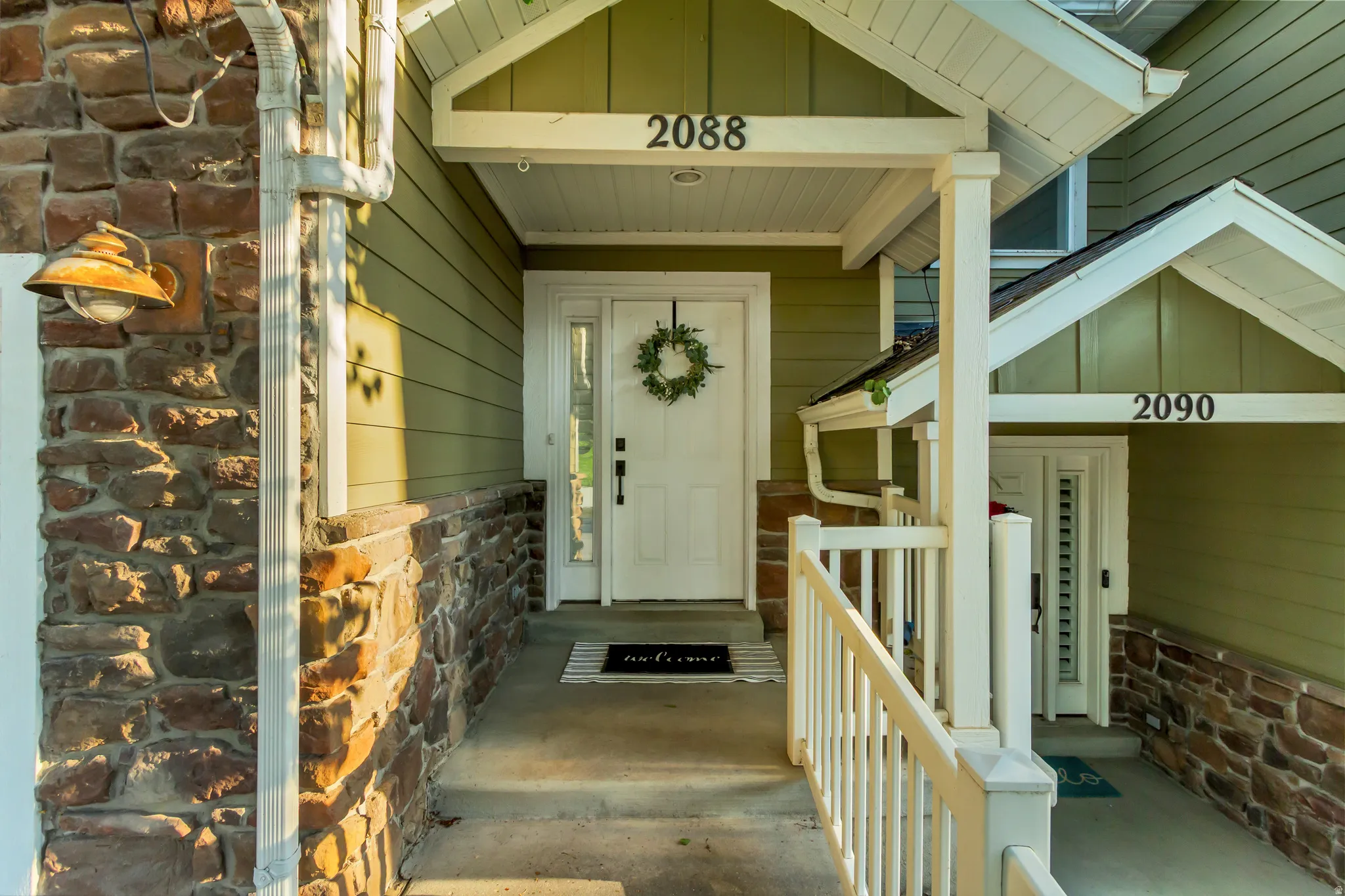 Stone and siding exterior with a covered entry, white front door, covered porch