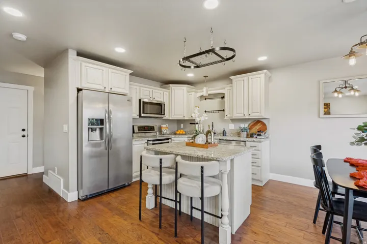 Kitchen featuring white cabinetry, stainless steel appliances, a center island and granite countertops