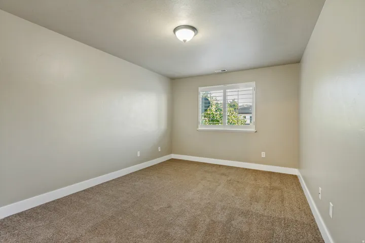 Wall-to-wall carpeting, light neutral wall color, white trim, window with white blinds, and a flush-mount ceiling light fixture