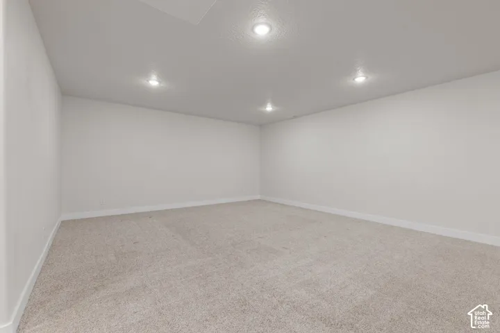 Recessed lighting illuminates neutral carpeting and light-toned walls
