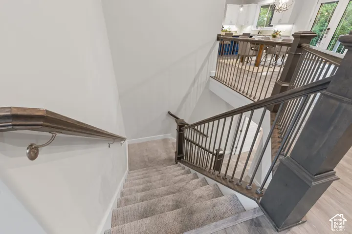 Carpeted staircase with an ornamental railing and wood newel posts