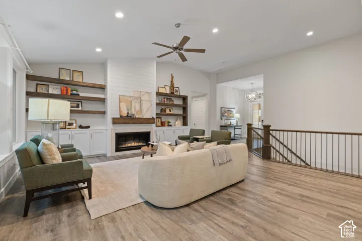 Spacious living area featuring high ceilings, wood-finish flooring, recessed lighting, and a fireplace with a wood mantle and built-in shelving