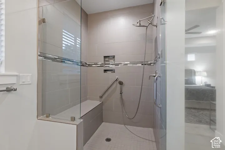 Shower with glass enclosure, built-in bench, tiled walls with decorative accent, and a dual-head shower system