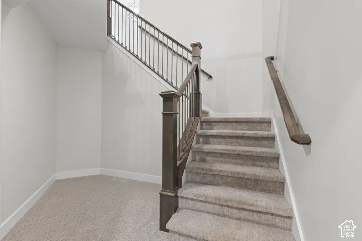 Carpeted staircase with dark wood newel posts and handrails