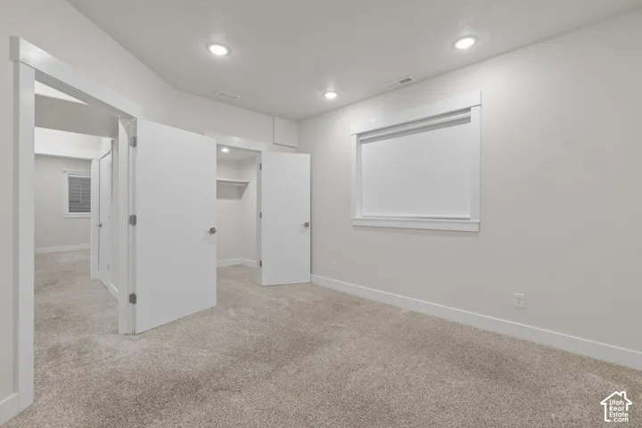 Plush carpeting with light-toned walls, recessed lighting, and a window with roller blinds