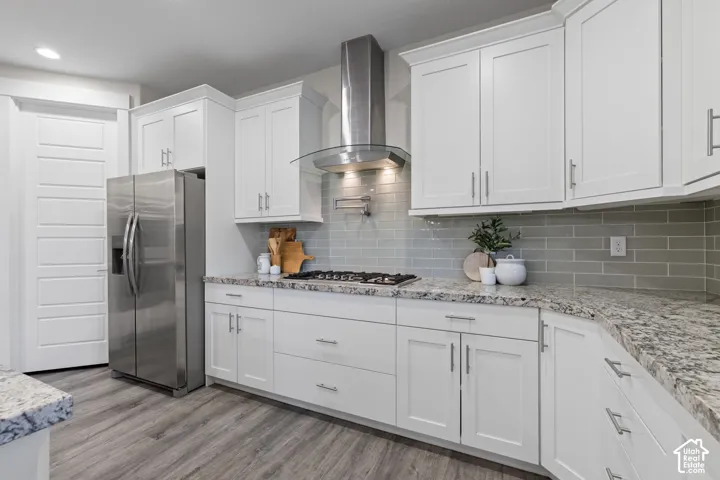 White shaker cabinetry, stainless steel appliances, granite countertops, subway tile backsplash, and wood-finish flooring