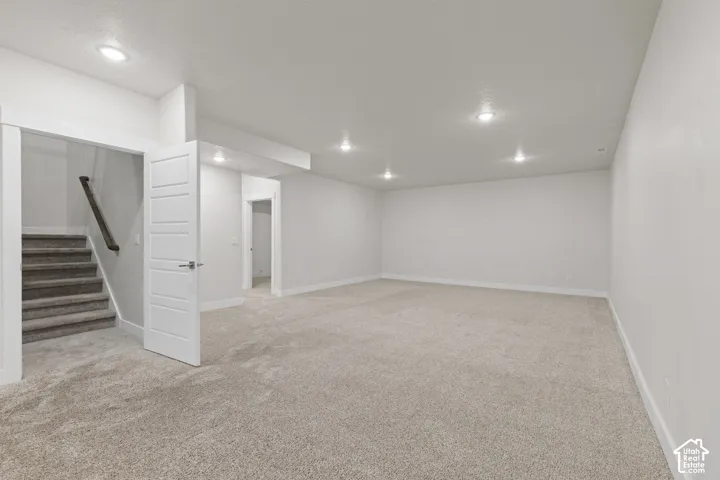 Expansive carpeted area with recessed lighting, white walls, and white trim
