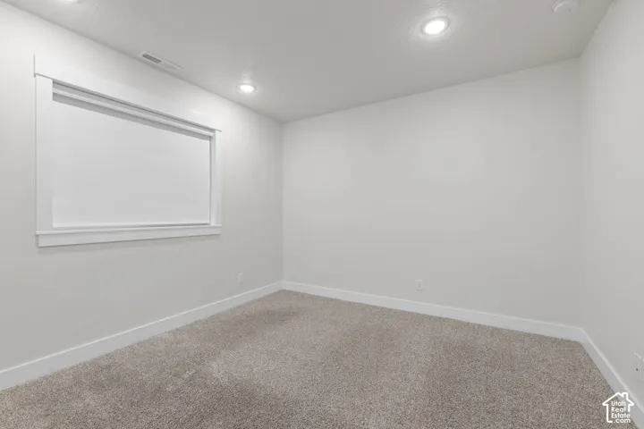 Recessed lighting, light-toned carpeting, window with white trim, and white walls