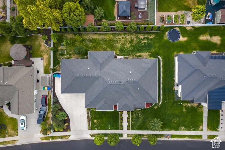 Asphalt shingle roofing, expansive green lawn, concrete driveway, mature trees, landscaped borders