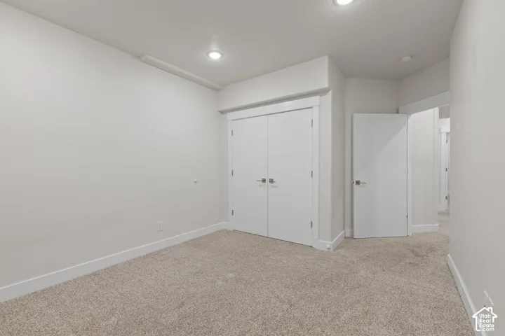 Recessed ceiling lighting, white interior doors, and neutral carpet flooring