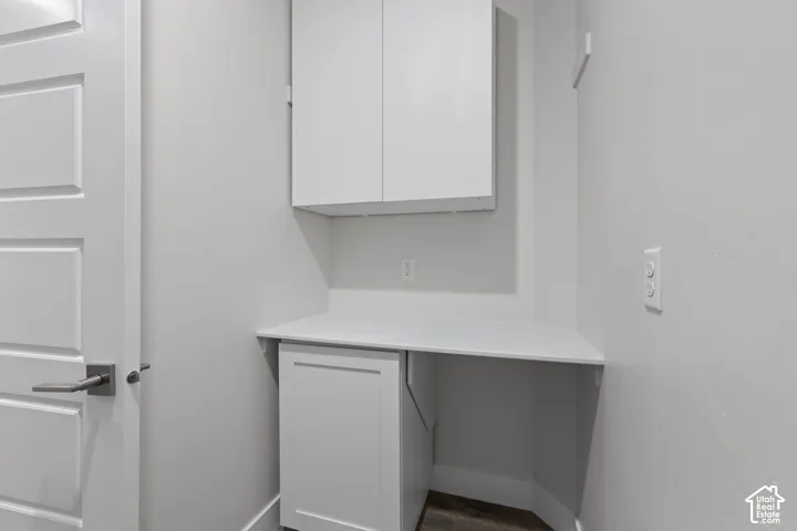 Built-in white cabinetry, white countertop, and dark wood-finish flooring