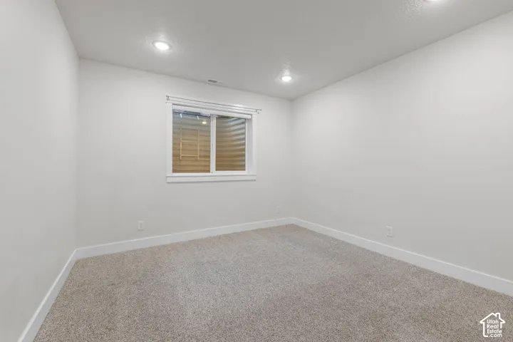 Recessed lighting, light-toned carpeting, white walls, and a white-framed window