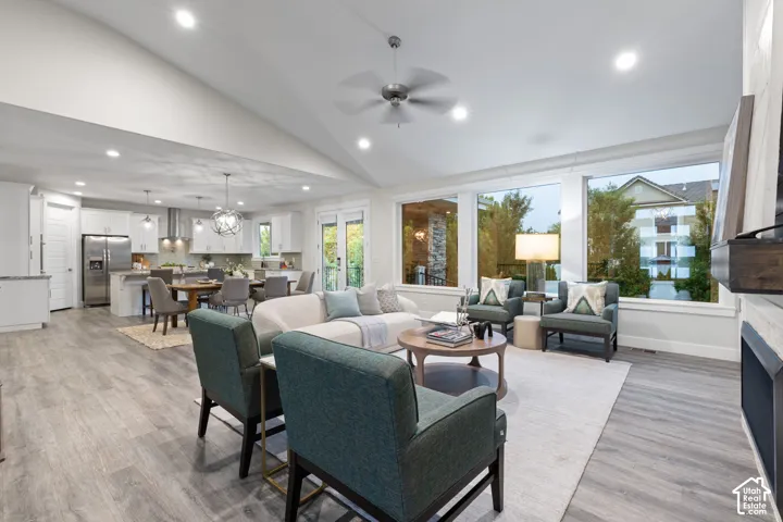 Vaulted ceiling with recessed lighting and ceiling fan, wood-finish flooring, white cabinetry, stainless steel appliances, and large windows
