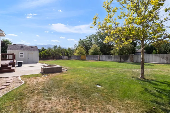Expansive backyard featuring a manicured lawn, concrete patio, and privacy fencing