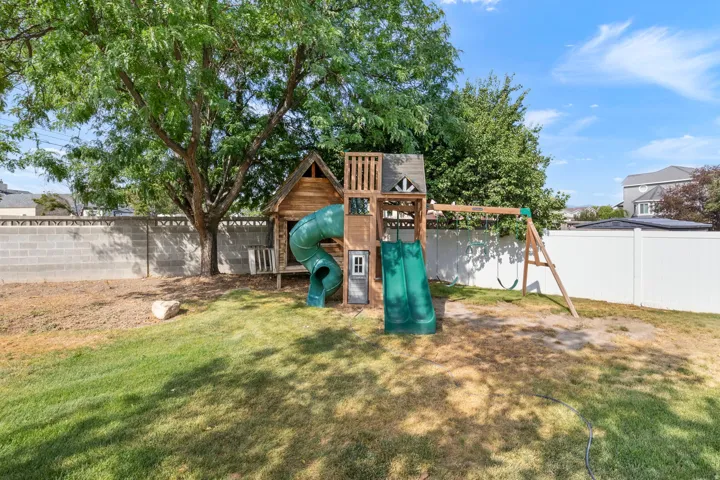 Expansive backyard featuring a mature tree, a full block privacy fence, and a white vinyl fence