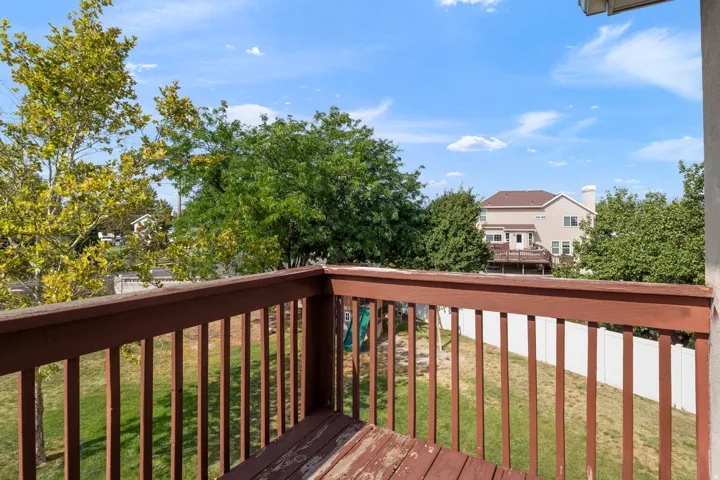 Outdoor deck with wood railings, overlooking a grassy yard with mature trees