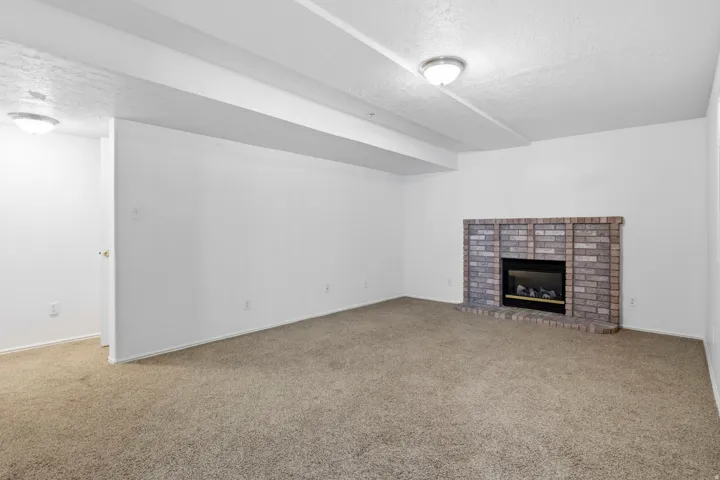 Built-in fireplace with a brick surround, light-colored carpeting, and recessed ceiling lighting