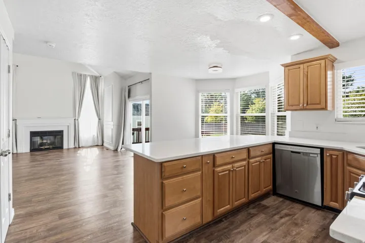 Open-concept kitchen with wood-finish flooring, ample cabinetry, white countertops, and a built-in dishwasher
