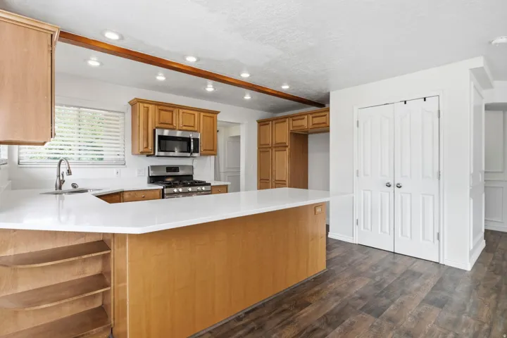 Kitchen featuring wood-finish flooring, recessed lighting, and a white countertop island with integrated shelving