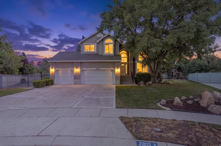 Stucco exterior with arched entry, two-car garage, and mature landscaping