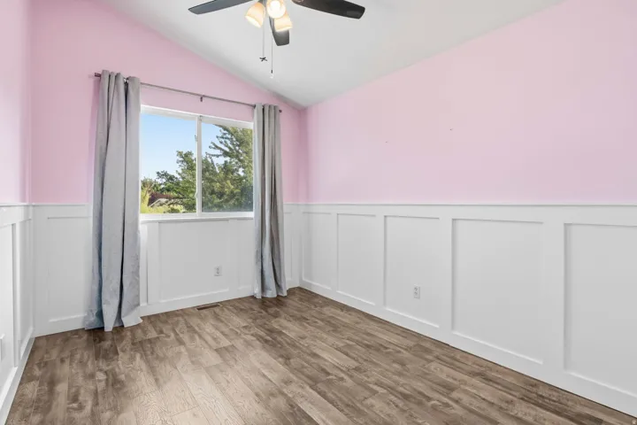 Wood-finish flooring with crisp white wainscoting and a vaulted ceiling