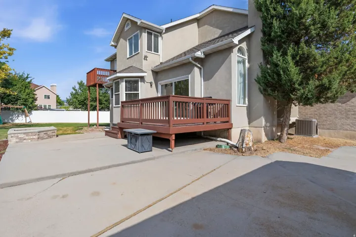 Rear exterior featuring a brown wood-finish deck, a concrete patio.