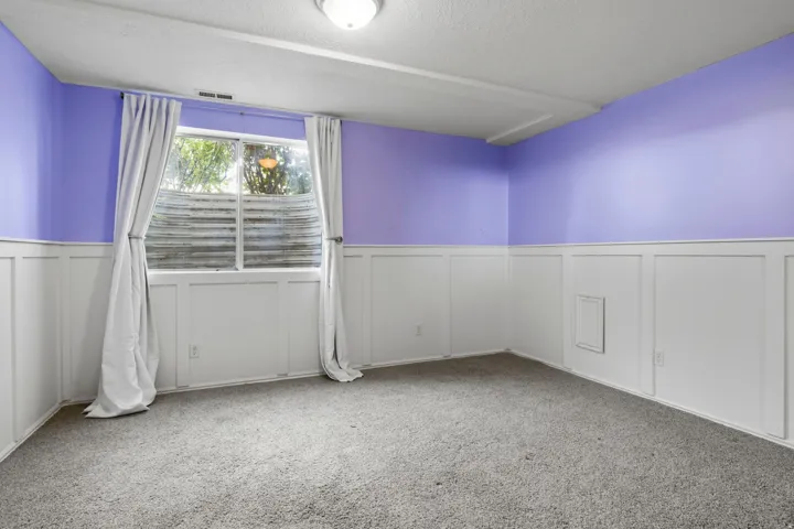 Board and batten wainscoting, light grey carpeting, recessed window, flush-mount ceiling light