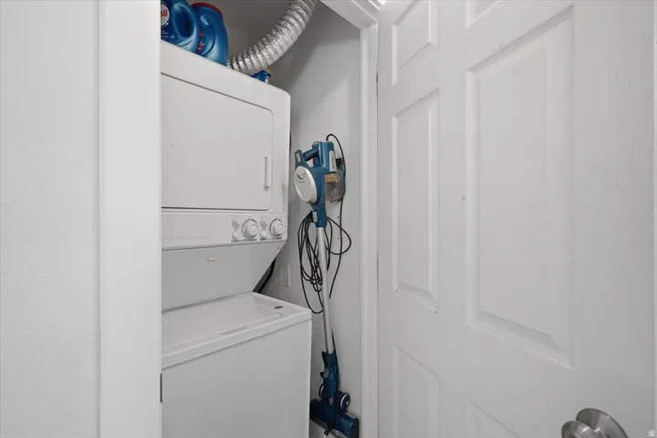 White stacked laundry appliances off hallway by bathroom and bedroom #2
