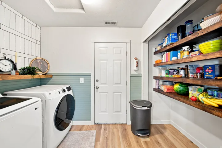 Wood-finish flooring with a paneled door, built-in open shelving, and a wall-mounted shelf