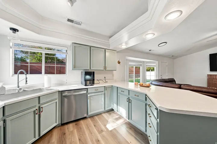 Expansive kitchen featuring light-toned cabinetry, light-toned countertops, wood-finish flooring, a stainless steel dishwasher, and recessed lighting
